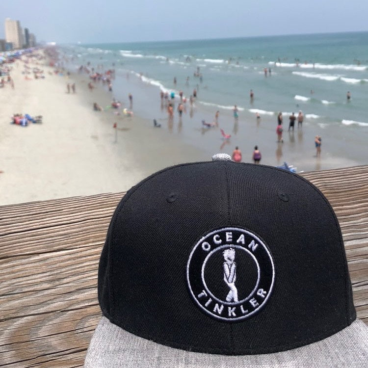black and grey ocean tinkler hat sitting on top of pier overlookng myrtle beach